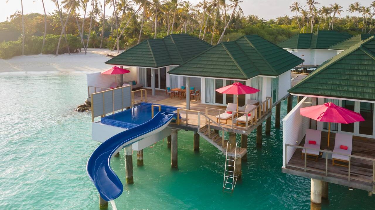 An overwater villa at Siyam World Maldives with lounge chairs and slide