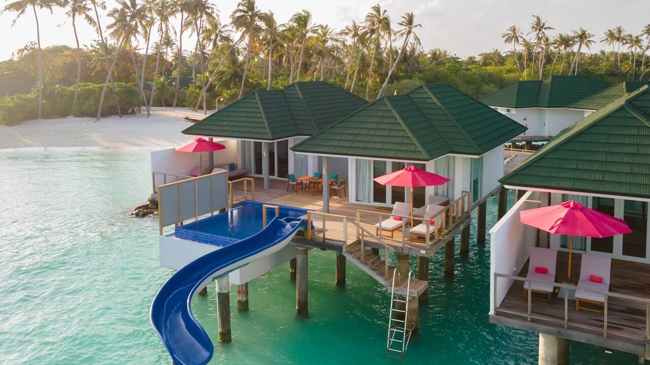 An overwater villa at Siyam World Maldives with lounge chairs and slide